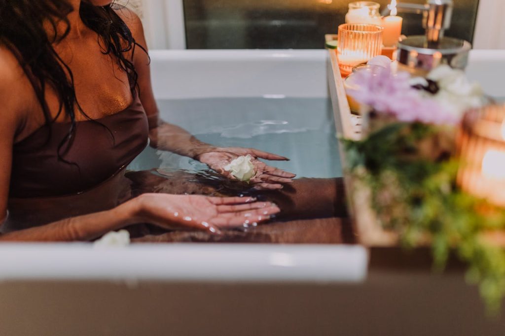 Serene spa bath experience with aromatic candles and fresh flowers promoting relaxation and tranquility.